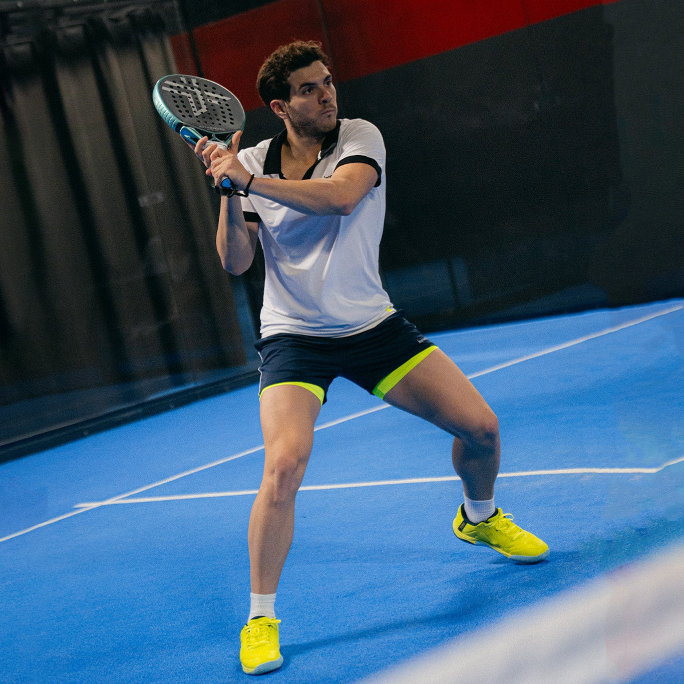 Man playing padel wearing neon green colour shoes.